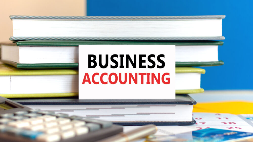 White card with text business accounting stands on the desk against books stacked, calculator, pen, credit card. Business and financial concept.