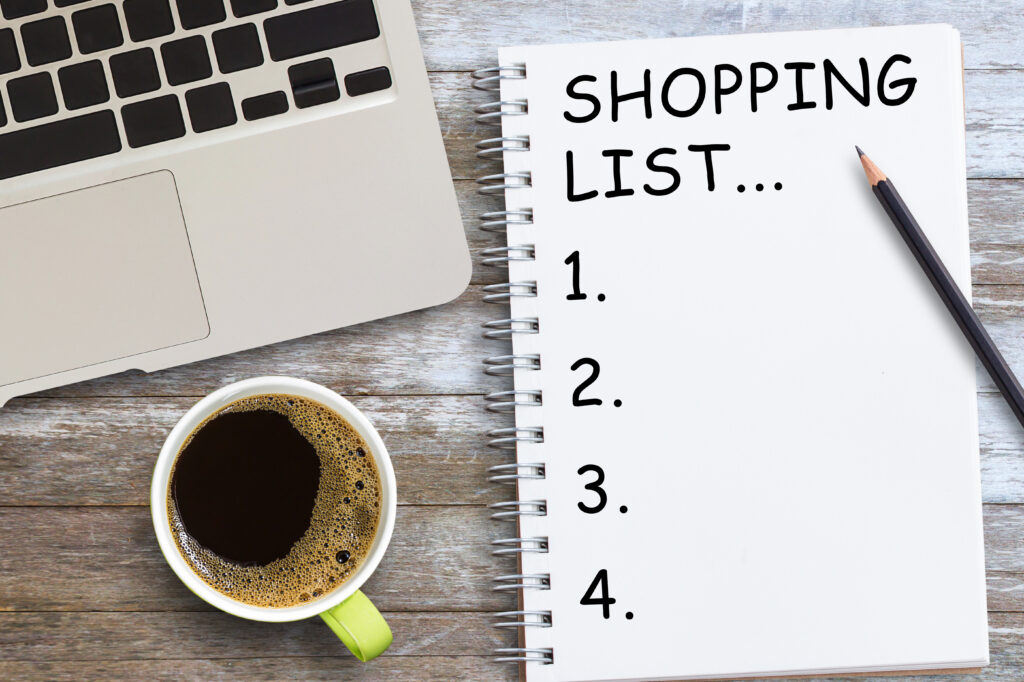 Shopping list in a notebook with and coffee on wood table