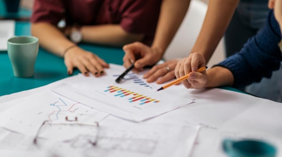 Image of people looking at charts on a table for the free forecasting fundamentals guide blog post by Brixx Software