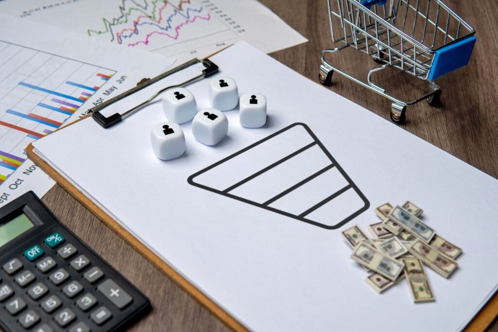 A clipboard with a sales funnel diagram and dice representing customers business concept