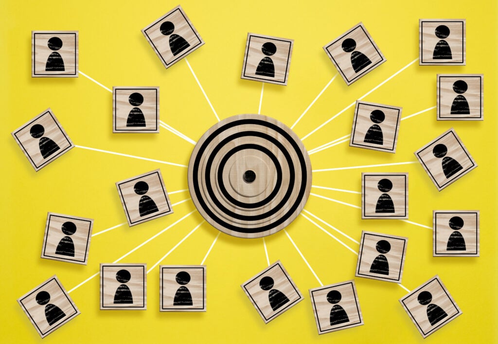 A wooden round target and wooden cubes with figure icon are connected symbolizing the concept of target audience identification
