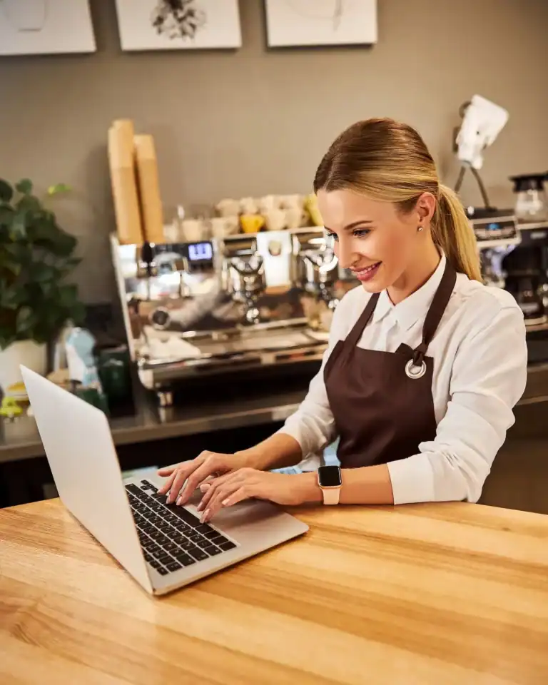 Friendly barista working on a laptop at Brixx coffee shop counter.