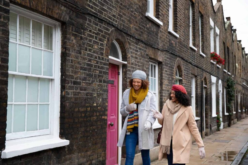 Charming women walking on a brick street in front of colourful houses in Brixx, enjoying a casual da.