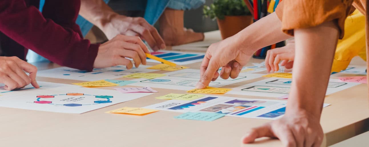 Group of people working together on a creative project at a table.
