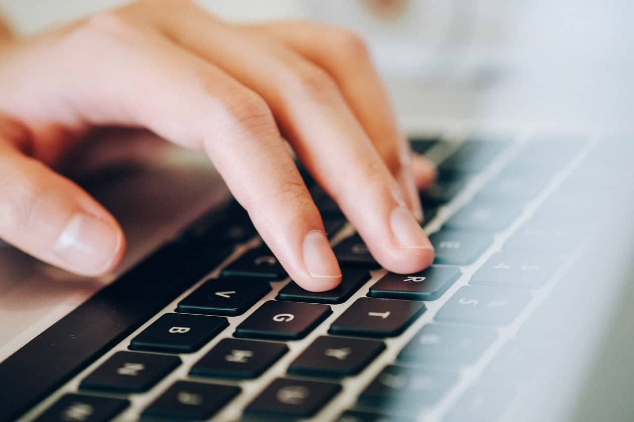 Close-up of a person's hand typing on a modern laptop keyboard at Brixx.