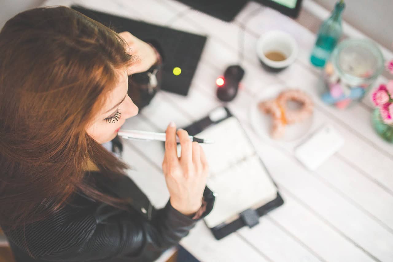 Woman working at Brixx co-working space with laptop and stationery.