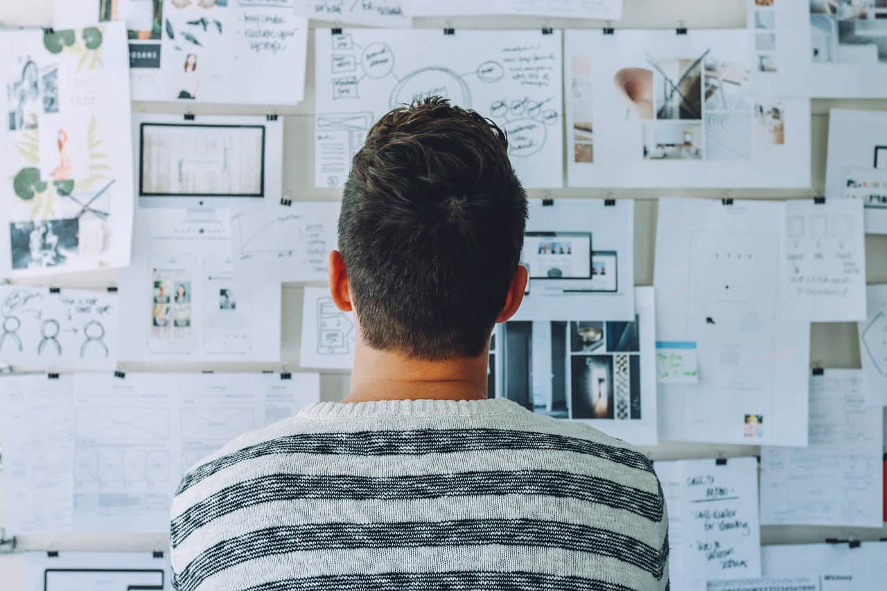 Person analyzing ideas on a wall of notes and sketches at Brixx workspace.