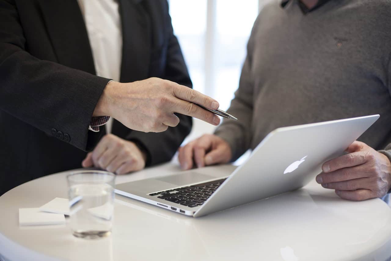 High-level business meeting with two professionals discussing on a laptop at a modern office.